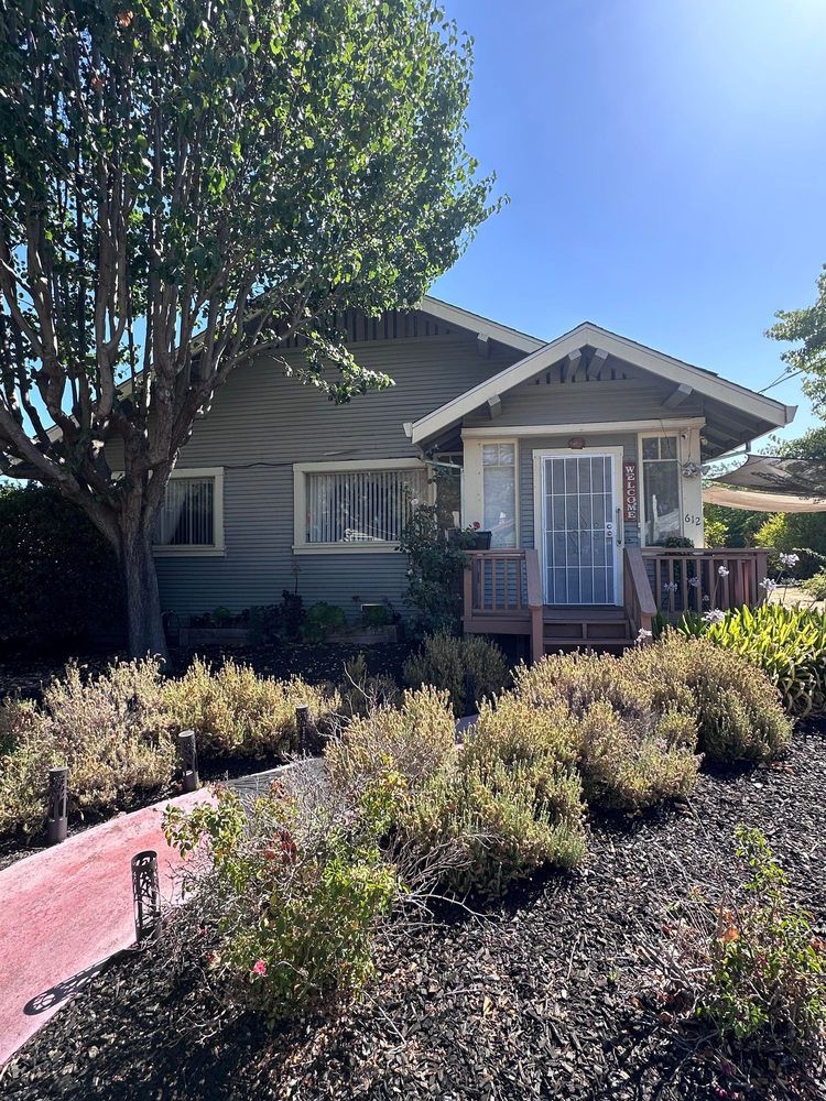 A quaint house with a nicely landscaped front yard under a clear blue sky.