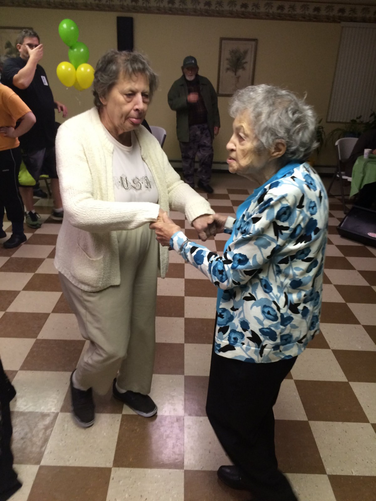 Two elderly individuals joyfully dancing at a social event.