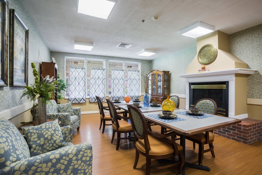 A cozy dining room with a large table, chairs, a fireplace, and decorative items.