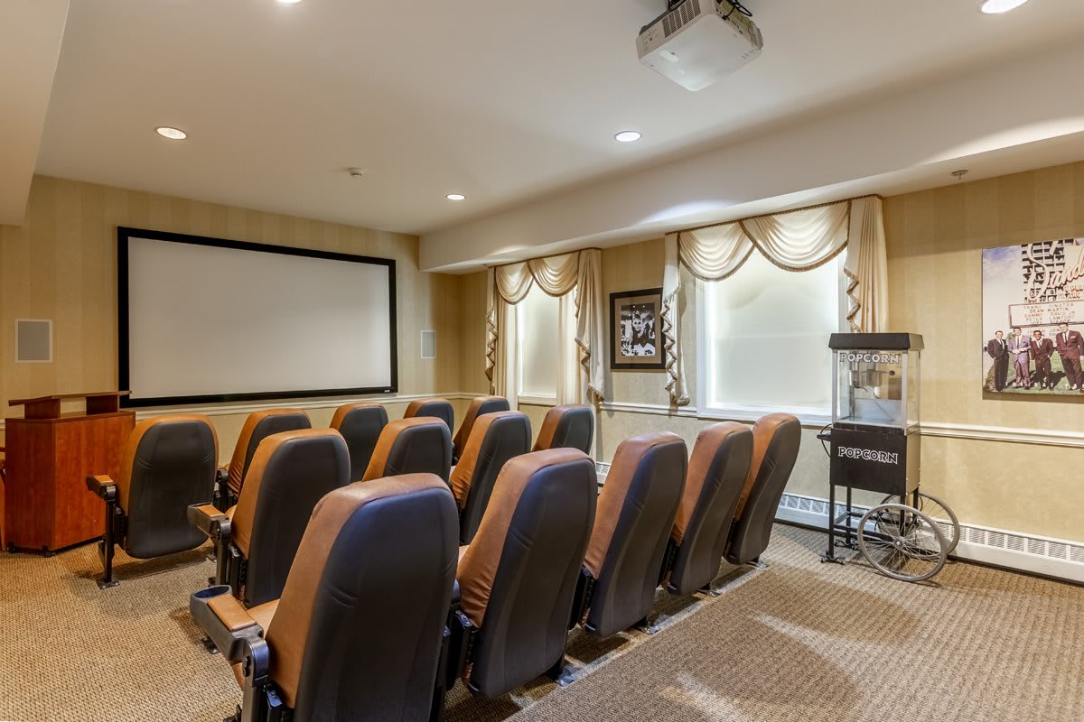 A cozy home theater with multiple rows of comfortable seating facing a large projection screen.