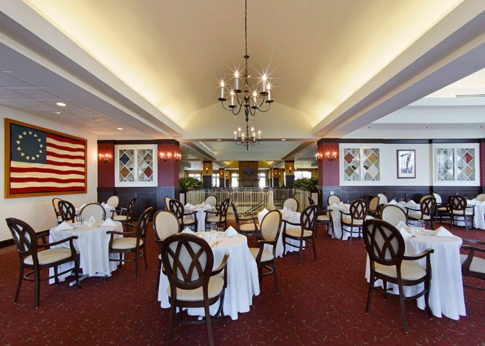 An elegant restaurant interior with tables and chairs arranged under a chandelier.