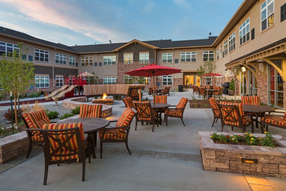 A residential building with a spacious outdoor patio featuring comfortable furniture and a fire pit during the evening.