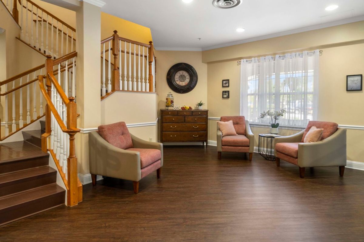 A cozy living room with comfortable chairs, warm lighting, and wooden flooring.