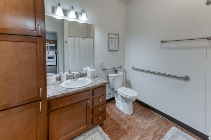 A modern bathroom with wooden cabinets and a large mirror.