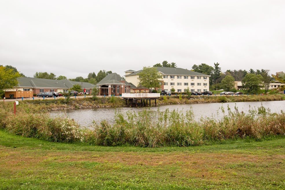 A serene view of a hotel near a pond surrounded by greenery.