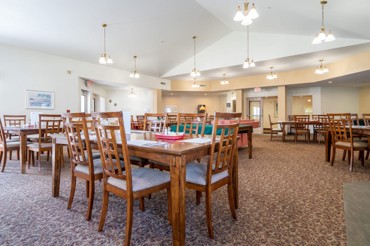 A spacious dining area with wooden tables and chairs, well-lit by ceiling lights.