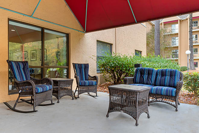 A cozy outdoor patio area with wicker furniture and a red awning.