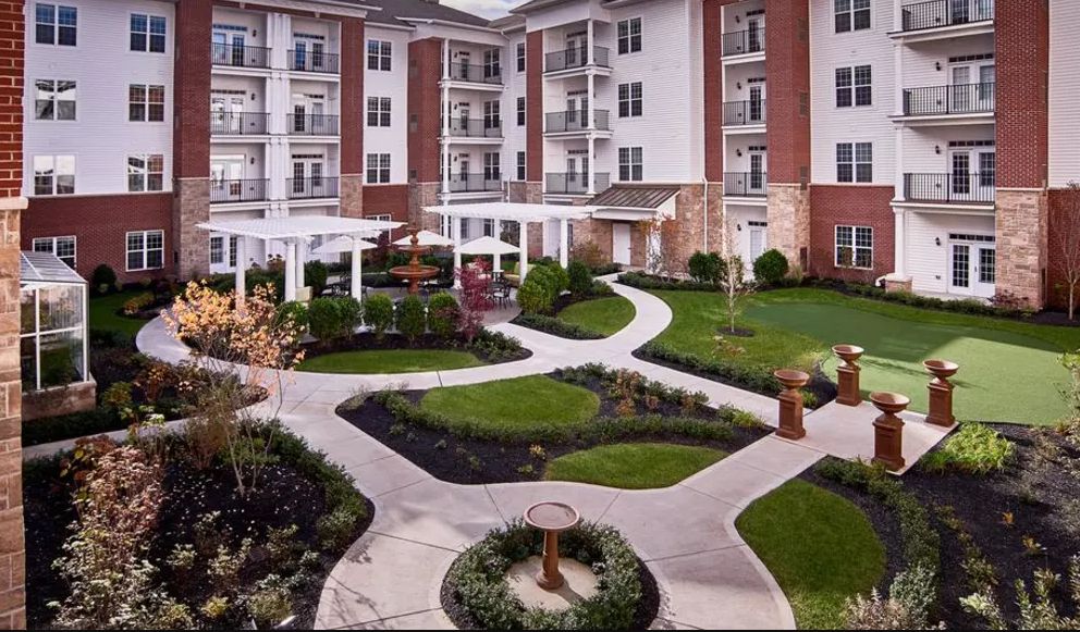 A modern apartment complex featuring a beautifully landscaped courtyard with winding pathways and vibrant greenery.