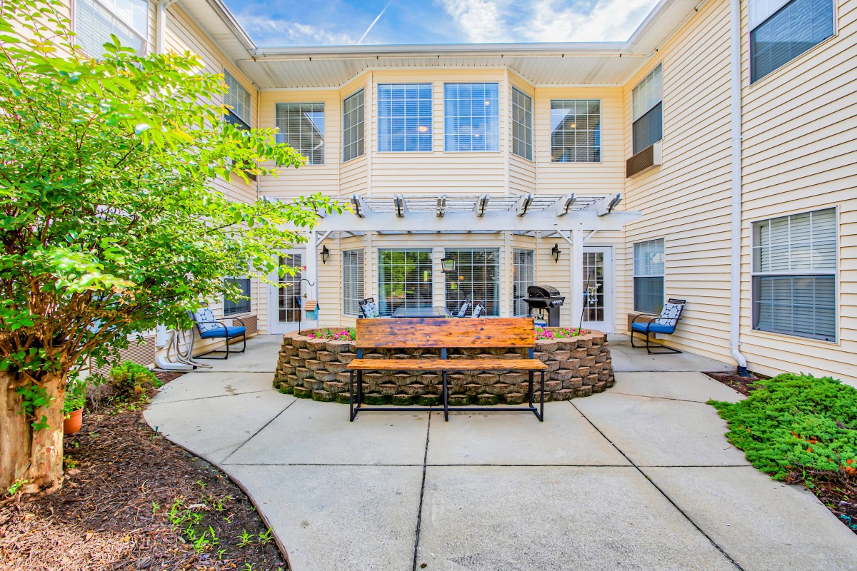 A cozy residential backyard patio with benches, a pergola, and landscaped surroundings.