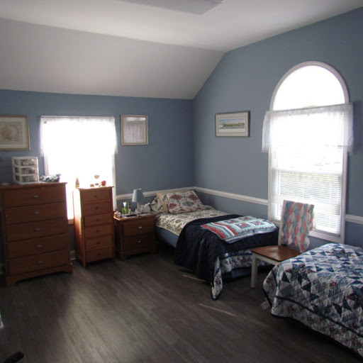 A cozy bedroom featuring two beds, blue walls, and ample natural light.