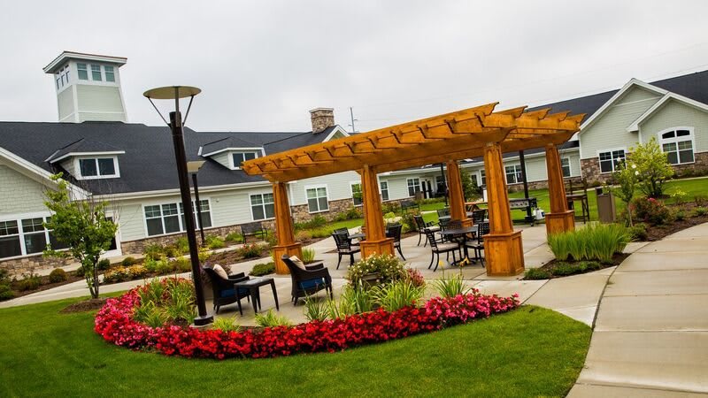 A well-maintained garden patio area with a wooden pergola, surrounded by landscaping and seating arrangements.