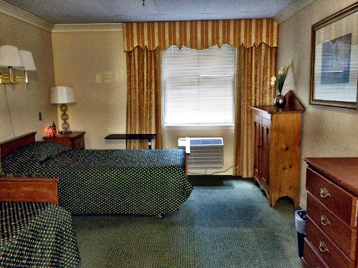 A cozy hotel room featuring a bed, window with curtains, and wooden furniture.