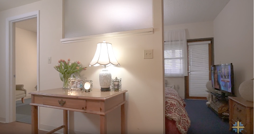 A cozy corner of a home featuring a decorative lamp, table, and fresh flowers.