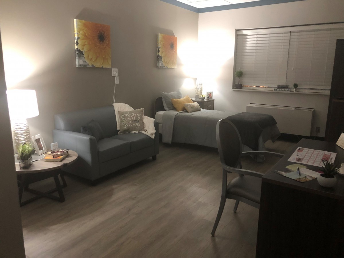 A cozy living space with a sofa, bed, and warm lighting.