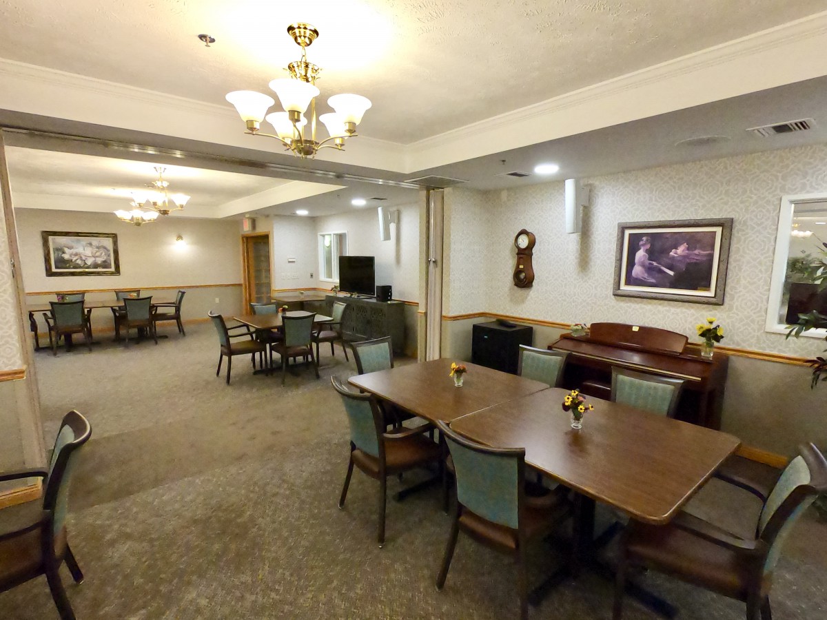 A spacious dining area with tables and chairs, featuring a chandelier and decorative wall art.
