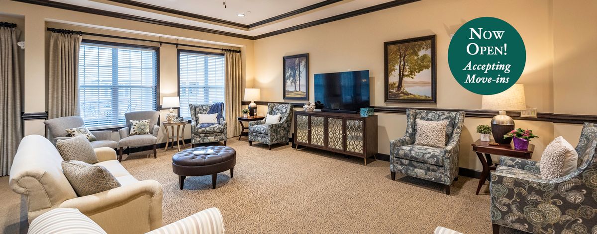 A cozy living room with elegant decor, featuring armchairs, a television, and artwork on the walls.