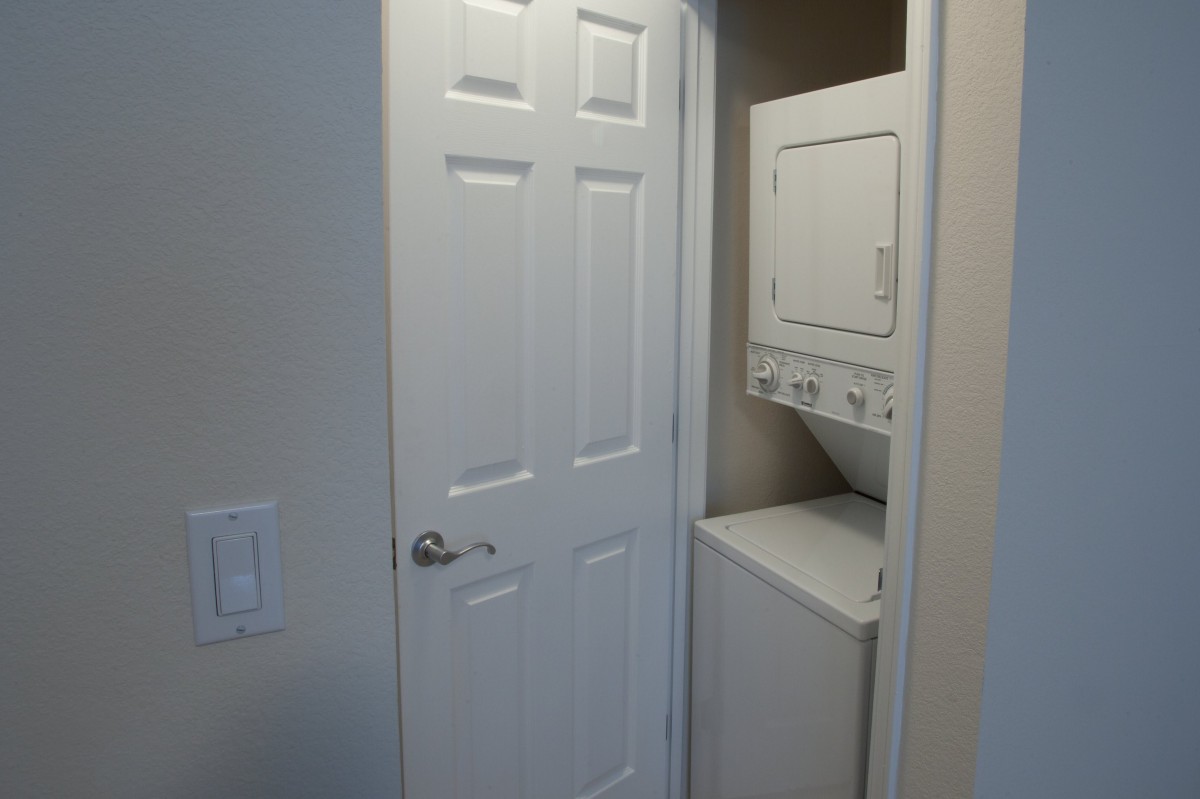 A compact laundry room with a stacked washer and dryer unit.