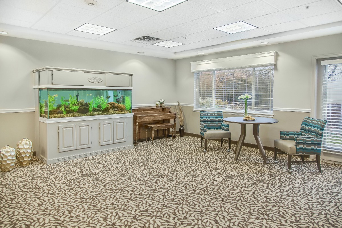 A cozy room featuring an aquarium, piano, and seating area with large windows.