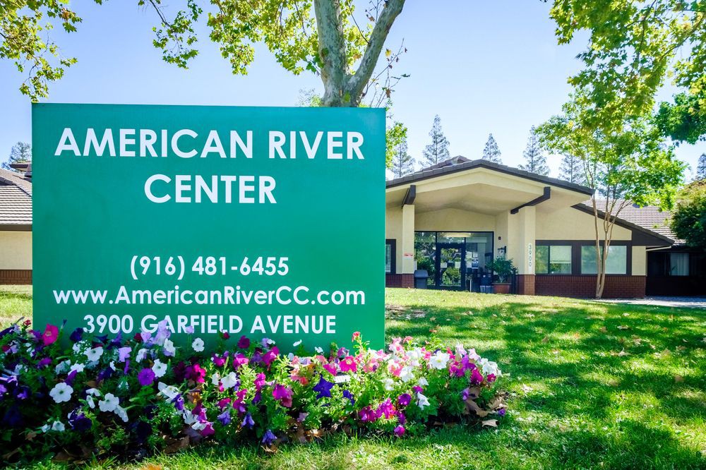 An outdoor view of the American River Center with a prominent sign and surrounding landscaping.