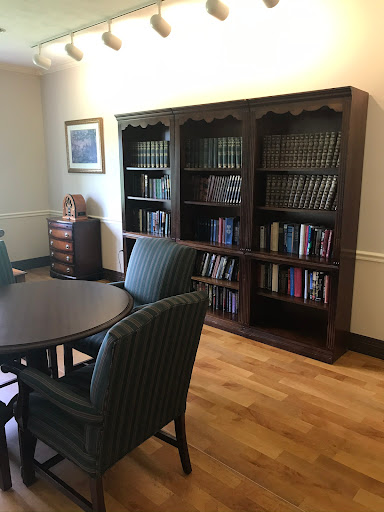 A cozy reading area featuring a wooden bookshelf filled with books, surrounded by a table and chairs.
