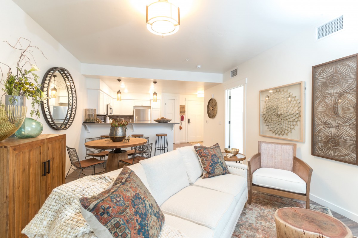 A modern living room with an open kitchen, featuring a white sofa and stylish decor.