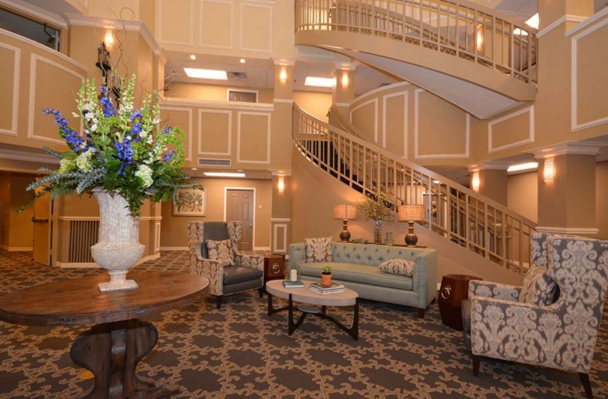 A luxurious lobby featuring elegant decor with a grand staircase, plush seating, and ornate lighting.