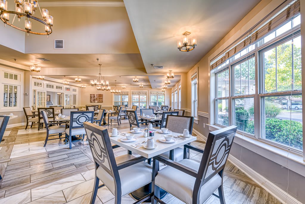 A cozy restaurant dining room with elegantly set tables and large windows.