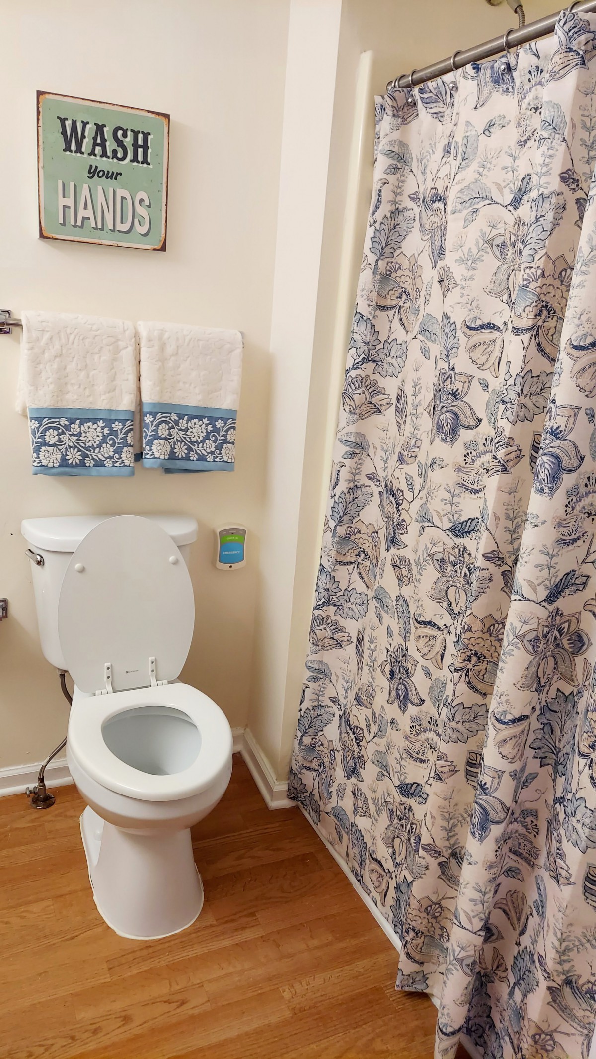 A bathroom with a toilet, patterned shower curtain, and neatly folded towels.