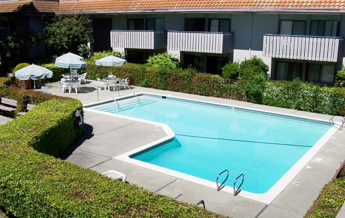 Outdoor swimming pool area at an apartment complex with patio furniture.