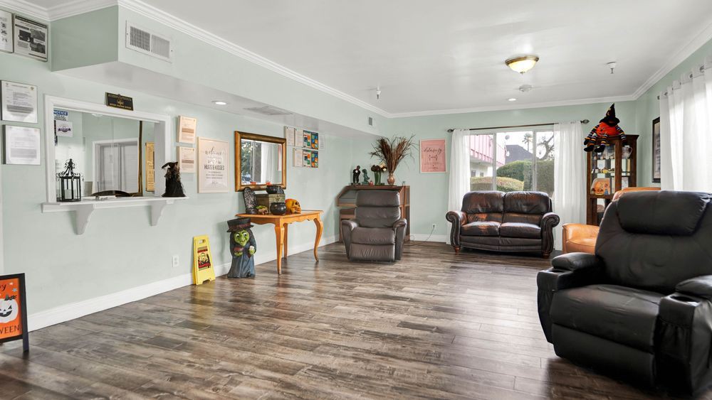 Spacious living room with hardwood floors, featuring a sofa, mirror, and decorative elements.