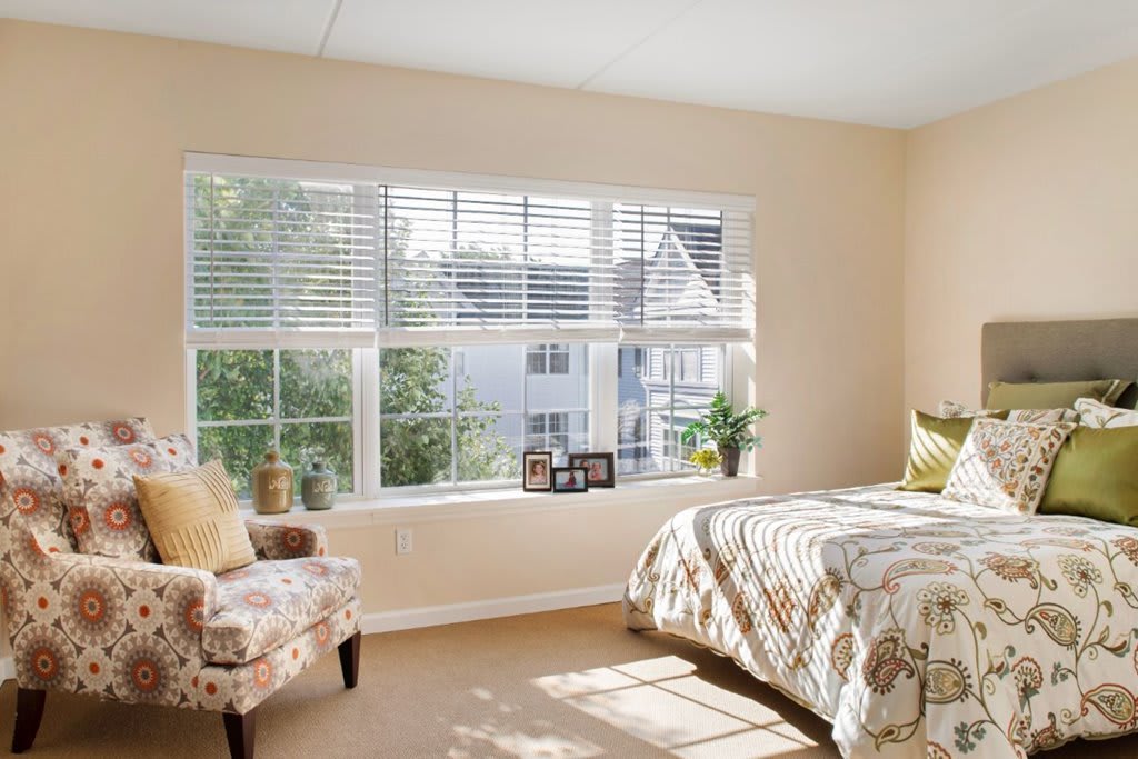 A cozy bedroom with a large window allowing natural sunlight to brighten the space.