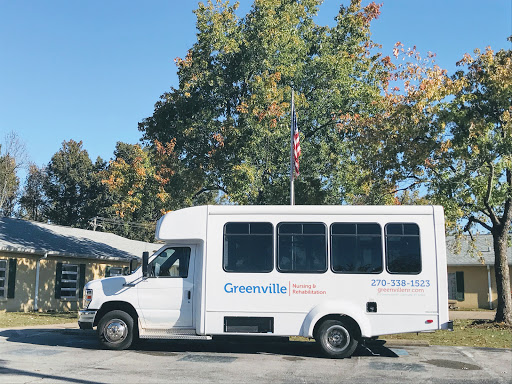 A white bus parked under colorful autumn trees, displaying an American flag.