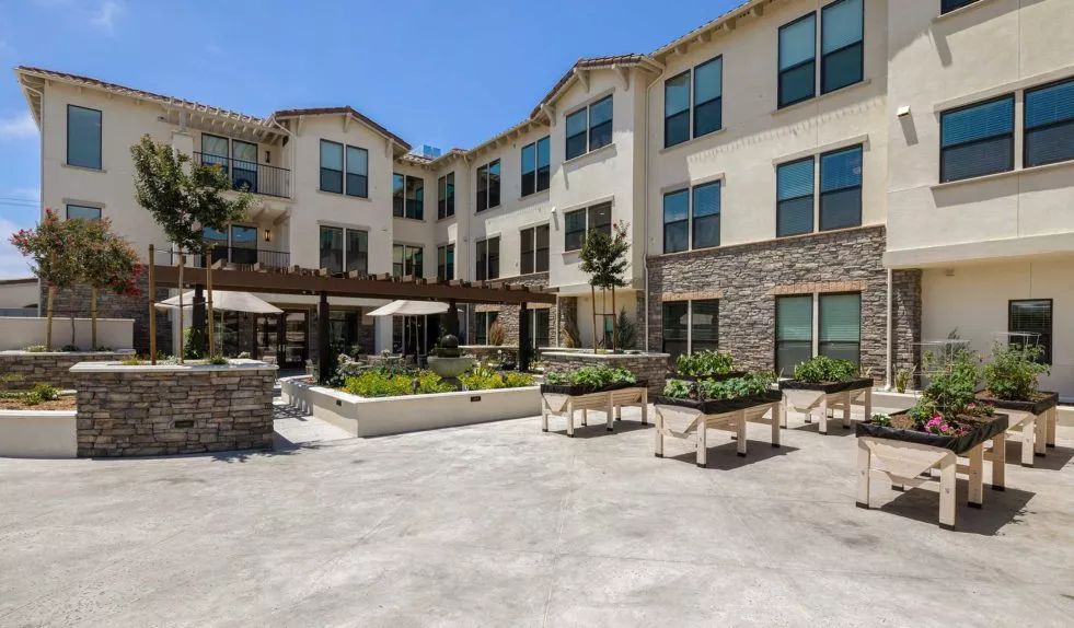A modern residential building with a spacious outdoor courtyard under a clear blue sky.