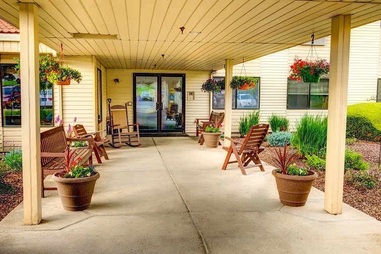 An inviting patio area with wooden chairs, potted plants, and hanging baskets.