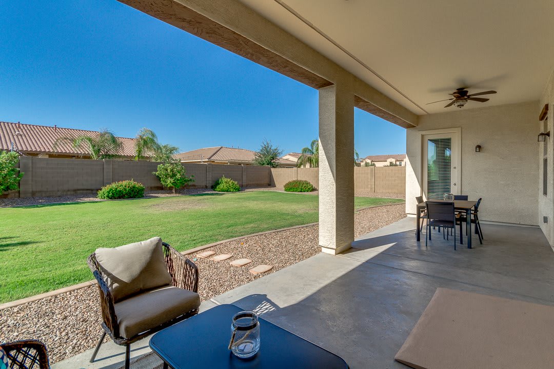 A spacious backyard patio with comfortable seating and a well-maintained lawn under a clear blue sky.