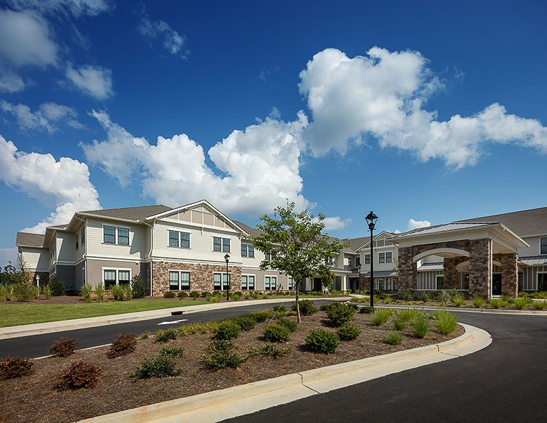 A modern residential building with landscaped surroundings under a partly cloudy sky.