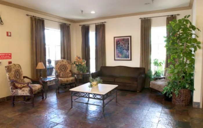 A cozy living room with a sofa, chairs, coffee table, and artwork on the wall.