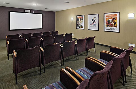 A cozy media room featuring comfortable seating, a projector screen, and movie posters on the walls, perfect for intimate screenings.