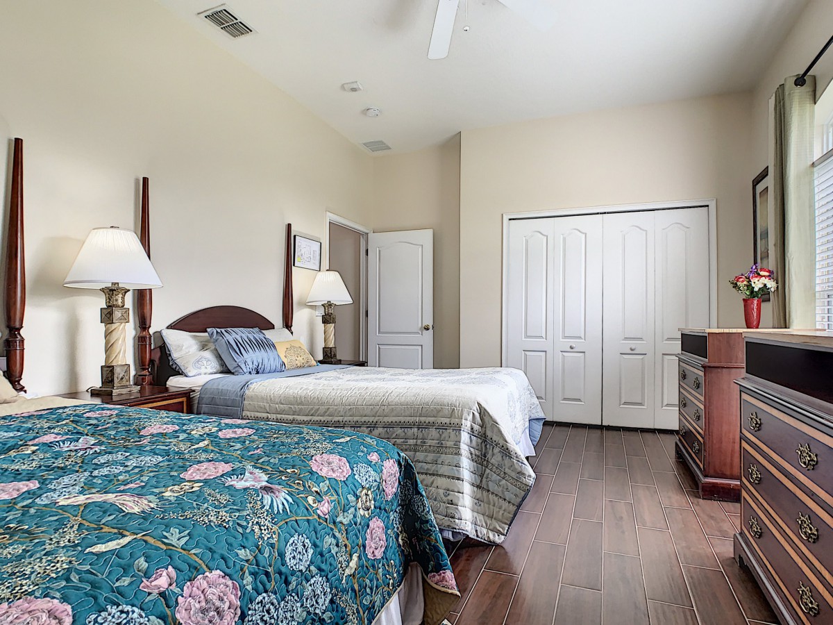 A cozy bedroom with two beds, wooden floors, and elegant decor.