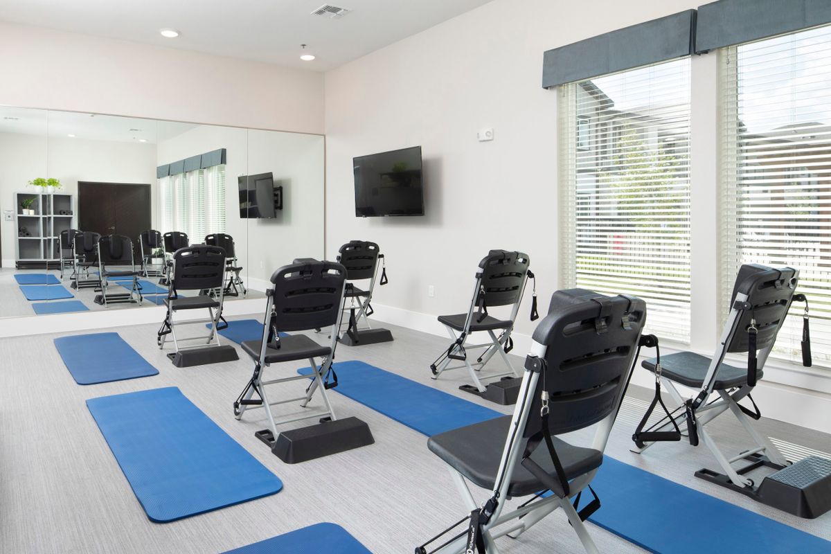 A well-equipped exercise room featuring yoga mats and chairs for fitness routines.