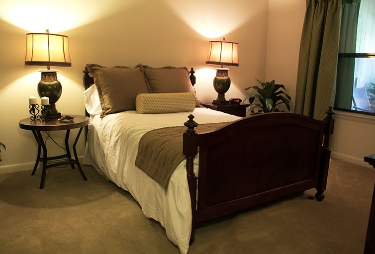 A cozy bedroom with a neatly made bed, warm lighting from lamps, and elegant decor.