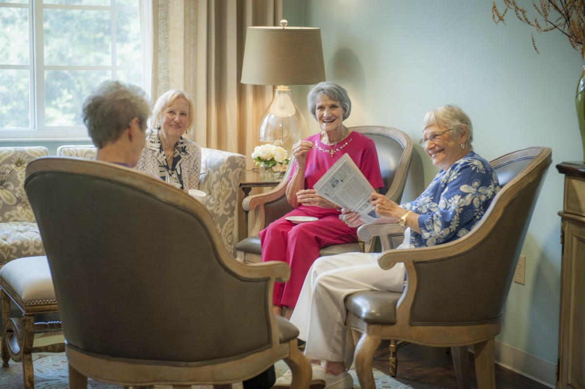 A group of seniors enjoying a conversation and reading indoors.