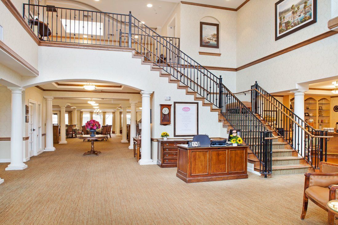 A spacious lobby area with a central wooden reception desk and an elegant staircase.