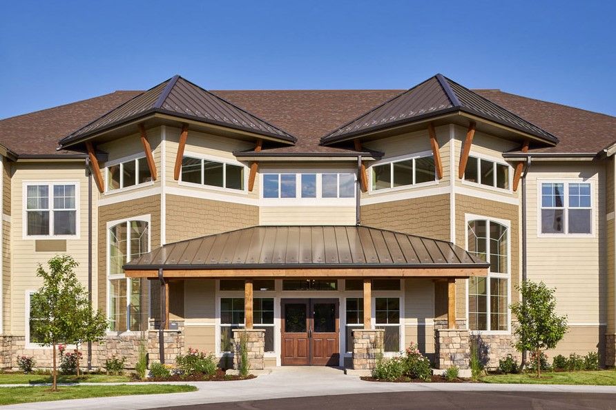 A modern, two-story residential building with wood accents and large windows.