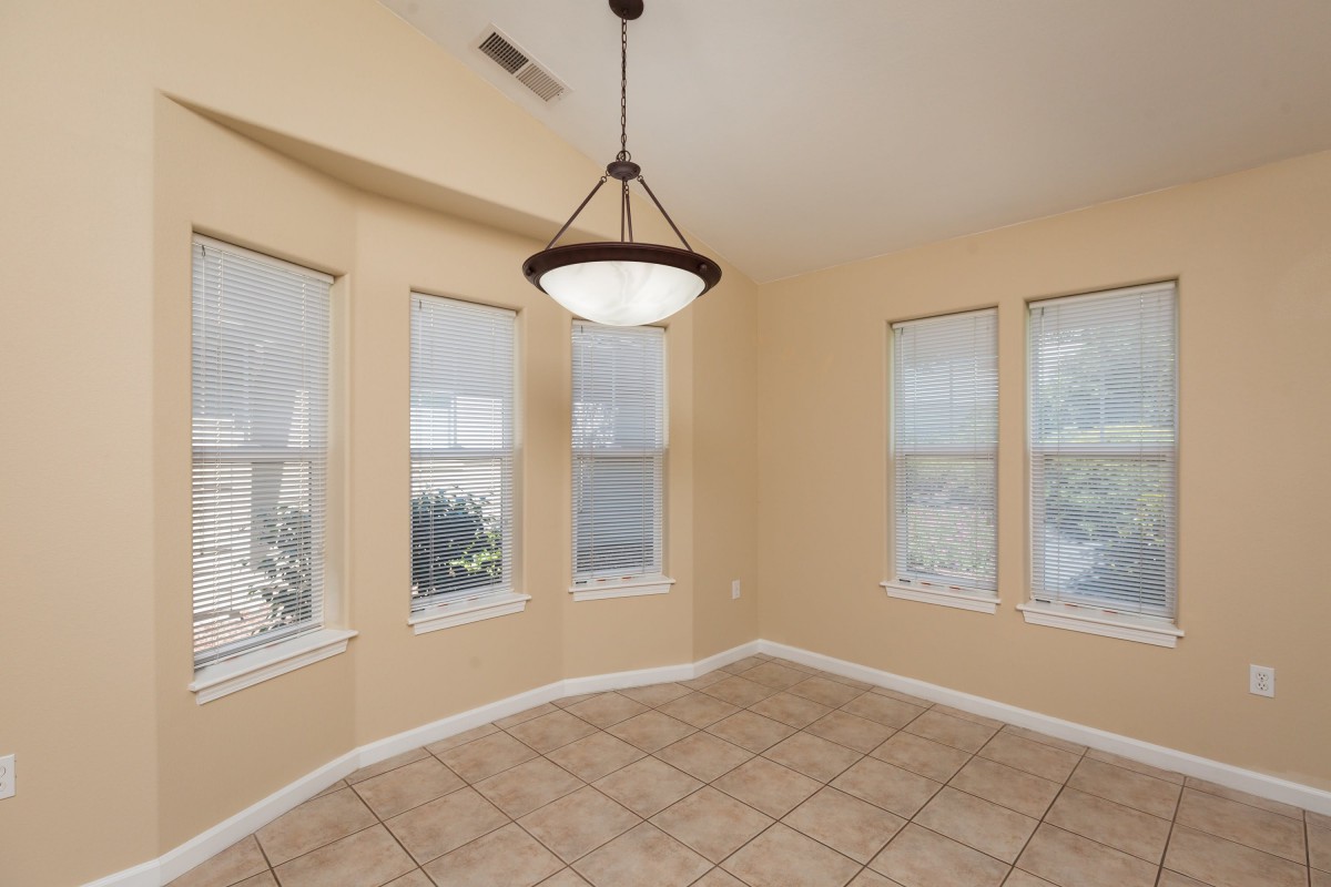 A bright, empty room with large windows and a central chandelier.