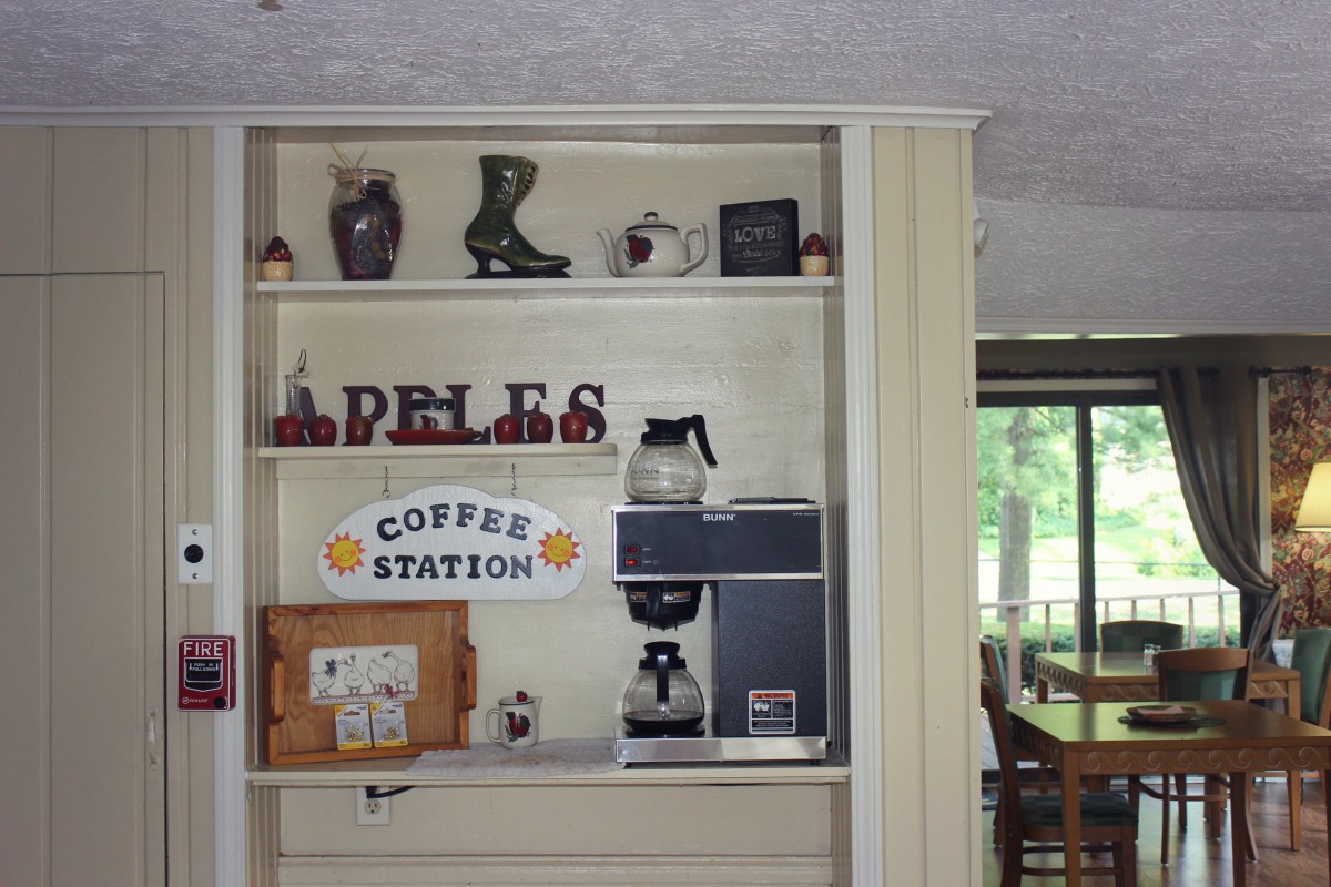 A cozy home kitchen setup featuring a coffee station with apple-themed decor.