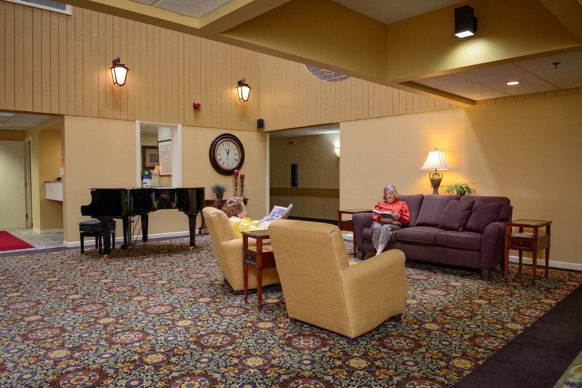 A cozy lobby with comfortable seating, a piano, and warm lighting.