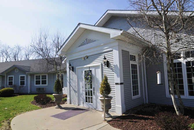A view of the front entrance of a residential building with white siding and decorative planters.