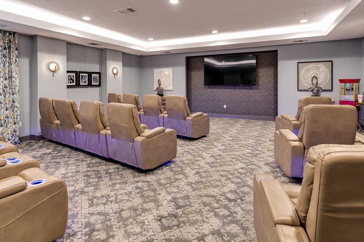 A modern theater room with recliner chairs and a large screen.