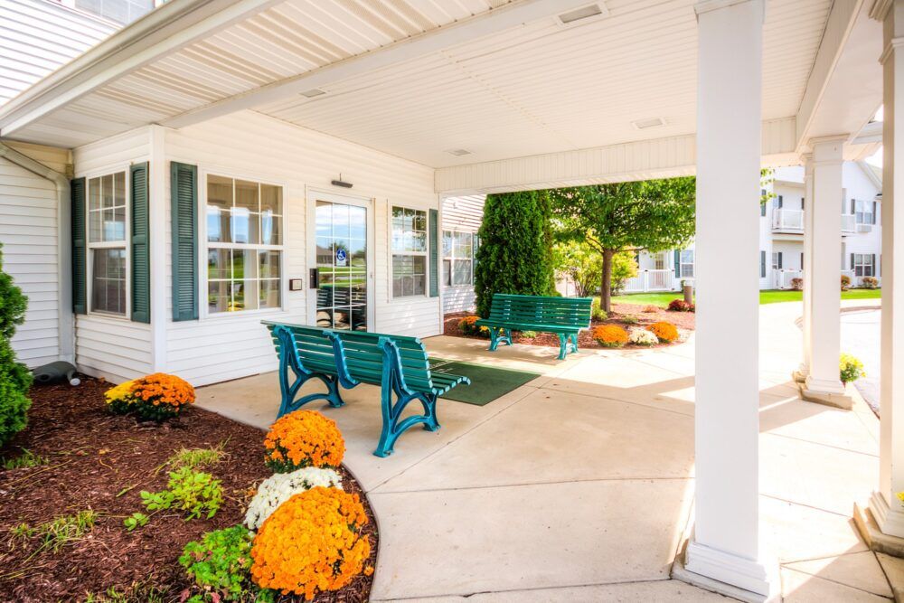A welcoming entrance with green benches and colorful flowers.